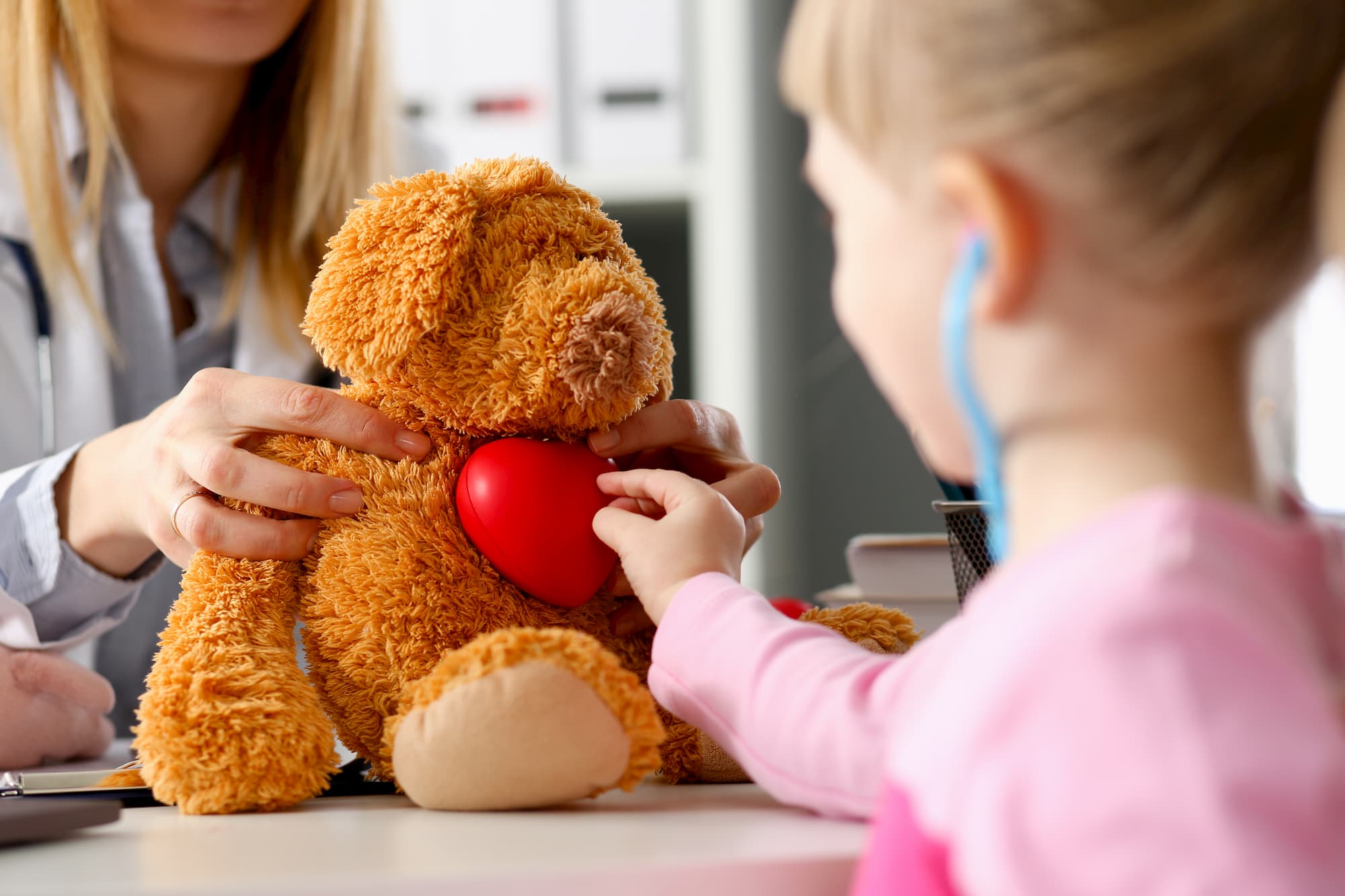 Child listening to teddy bear chest with stethoscope